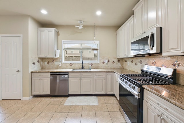 kitchen with light stone countertops, light tile patterned floors, white cabinets, appliances with stainless steel finishes, and sink