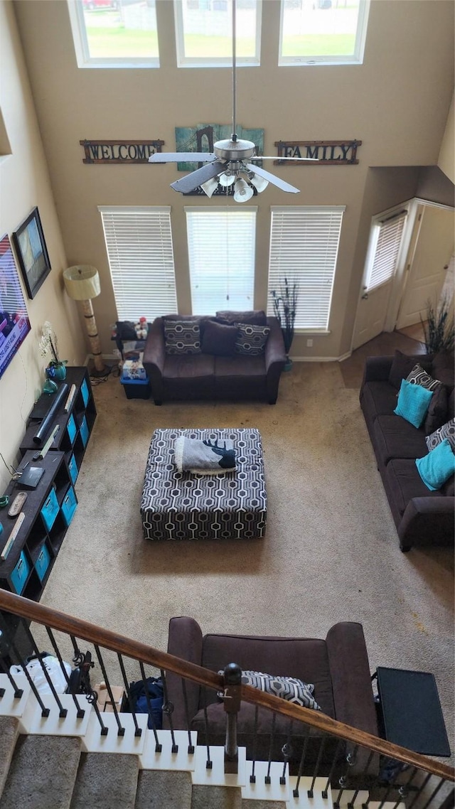 carpeted living room featuring a high ceiling and ceiling fan