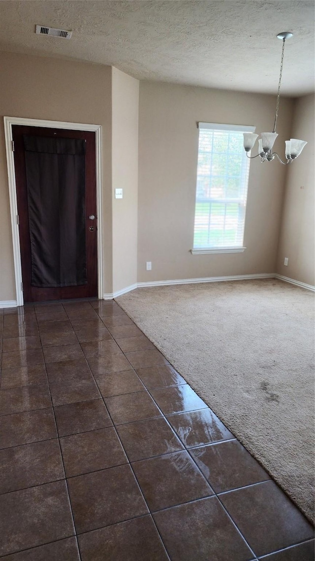 interior space with a textured ceiling, dark tile patterned floors, and a chandelier