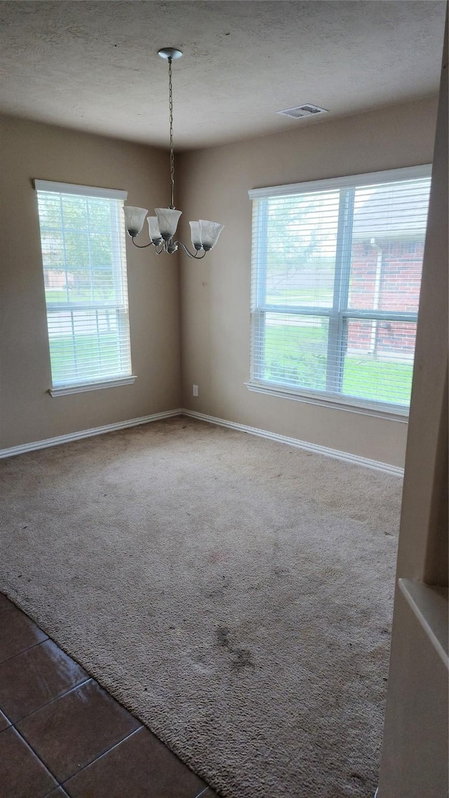 tiled empty room with a notable chandelier