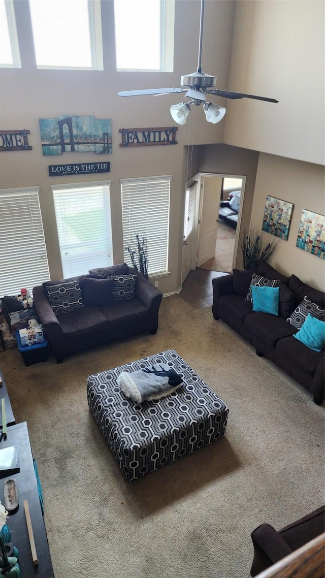 living room with a towering ceiling, carpet flooring, and ceiling fan