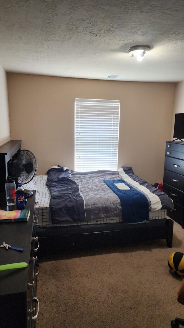 bedroom featuring a textured ceiling and dark colored carpet