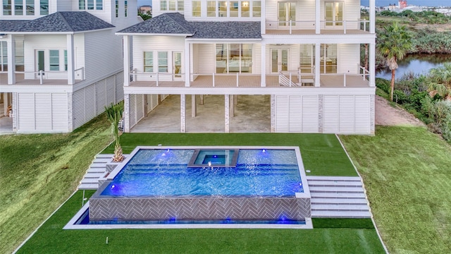 back of property featuring a balcony, a patio area, an in ground hot tub, and a lawn