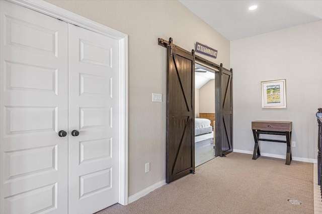 hallway with light colored carpet and a barn door