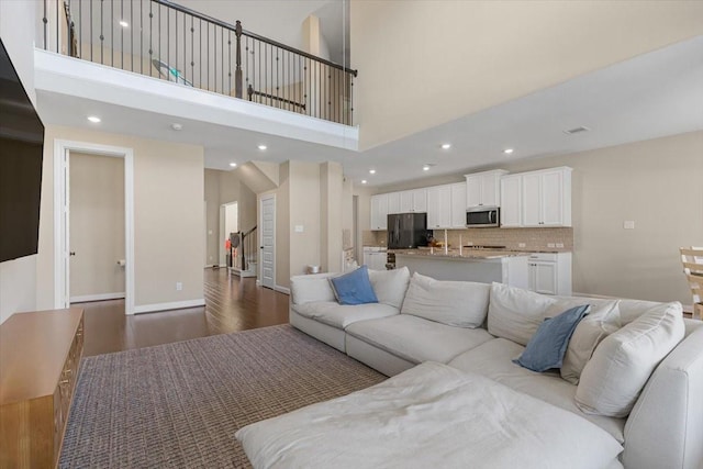 living room featuring a towering ceiling and hardwood / wood-style floors