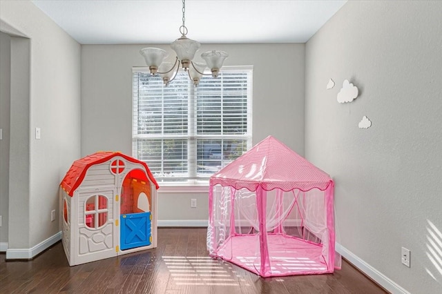 playroom featuring dark hardwood / wood-style flooring and a chandelier