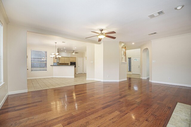 unfurnished living room with ceiling fan with notable chandelier, hardwood / wood-style floors, and crown molding