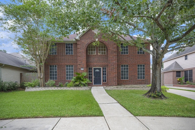 colonial-style house featuring a front yard and brick siding