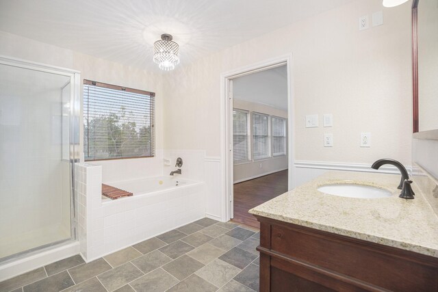 bathroom with shower with separate bathtub, a notable chandelier, and vanity