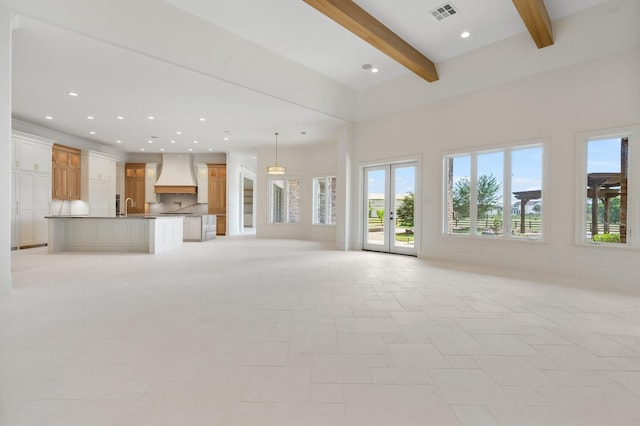 unfurnished living room featuring sink, french doors, and beam ceiling