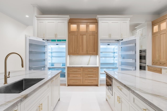 kitchen featuring white cabinets, light stone countertops, decorative backsplash, and sink