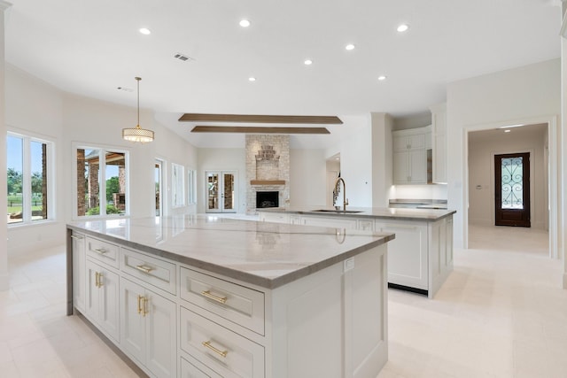 kitchen featuring sink, a large island, white cabinets, and hanging light fixtures