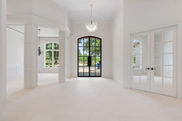 entrance foyer with french doors, crown molding, plenty of natural light, and a notable chandelier