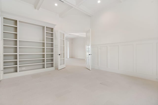 unfurnished room featuring beamed ceiling, french doors, coffered ceiling, and built in shelves