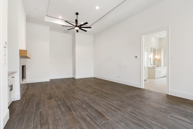 unfurnished living room featuring wood-type flooring, a raised ceiling, and ceiling fan