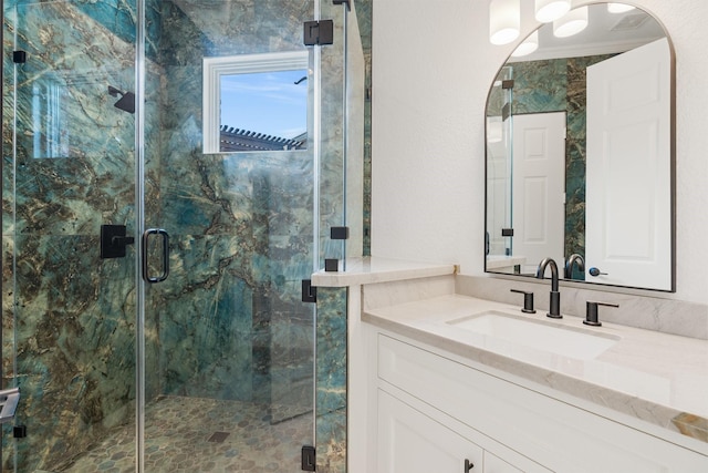 bathroom featuring a shower with door and vanity