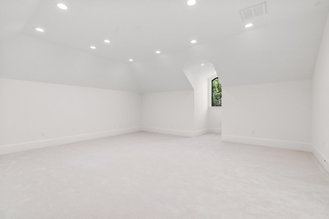 additional living space with light colored carpet and vaulted ceiling