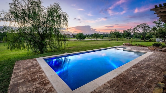 pool at dusk with a yard and a patio area