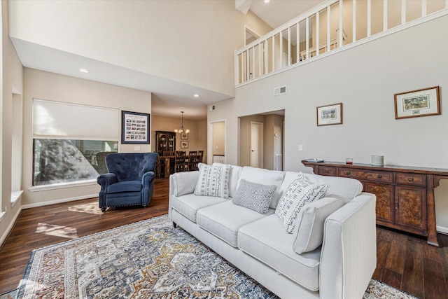 living room featuring a high ceiling, an inviting chandelier, and dark hardwood / wood-style flooring