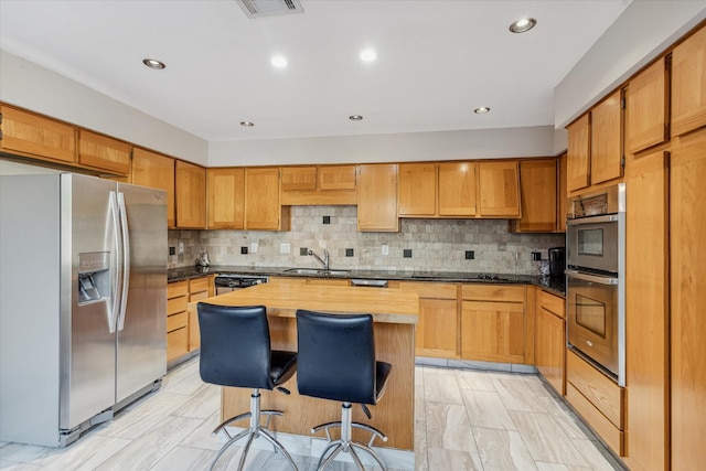 kitchen featuring stainless steel appliances, a center island, tasteful backsplash, and a kitchen breakfast bar