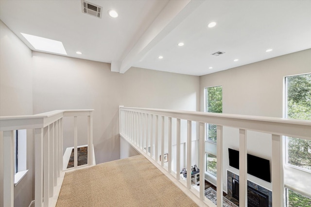 hallway featuring beam ceiling and a skylight