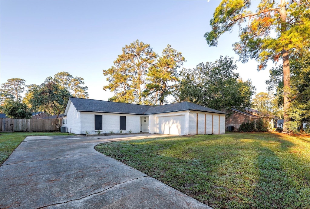 view of front of property featuring a garage, central AC, and a front lawn