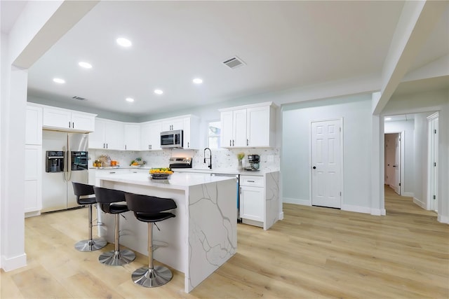 kitchen with appliances with stainless steel finishes, white cabinets, a center island, and decorative backsplash