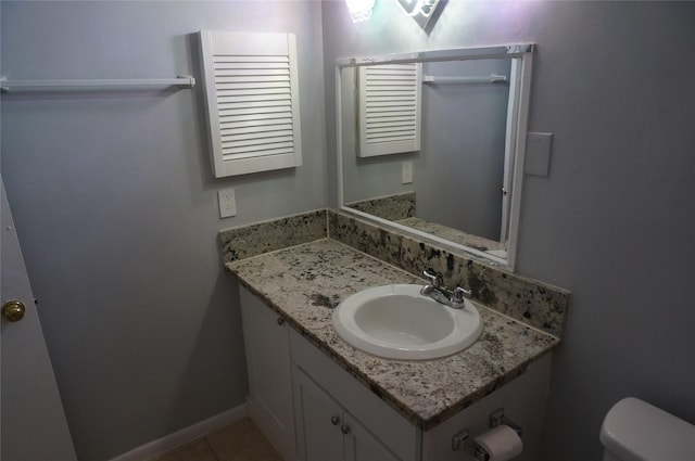 bathroom with toilet, vanity, and tile patterned flooring