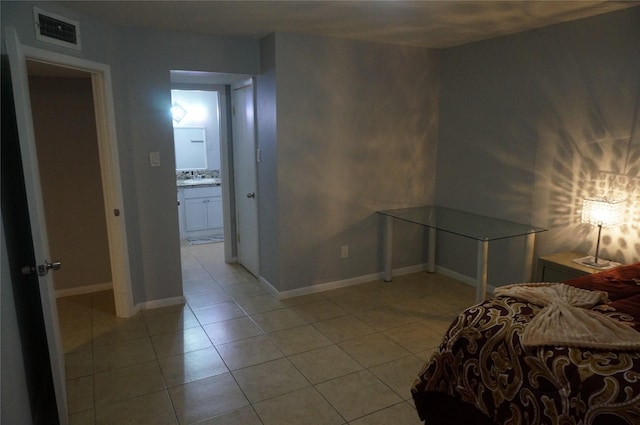 bedroom with ensuite bath and light tile patterned floors