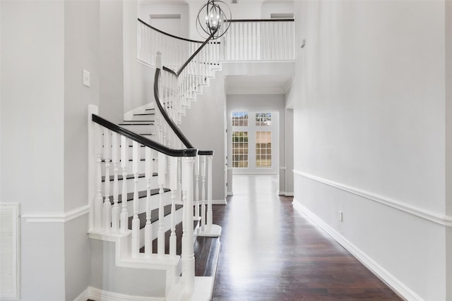 staircase with a notable chandelier, hardwood / wood-style floors, and crown molding