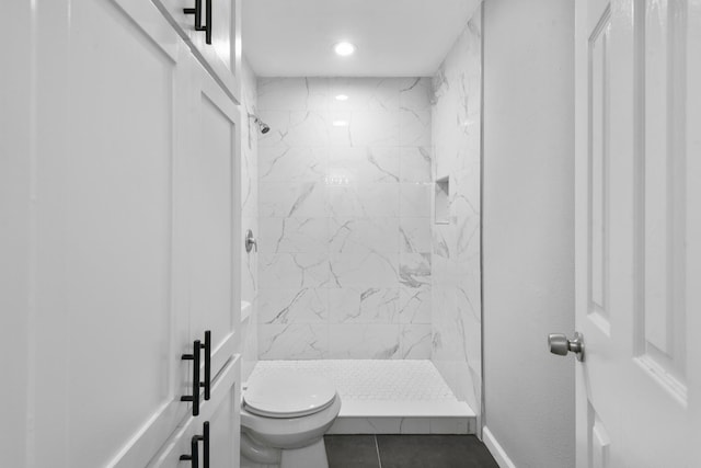 bathroom with a tile shower, tile patterned floors, and toilet