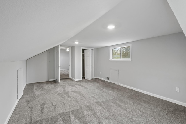 bonus room featuring vaulted ceiling and light colored carpet