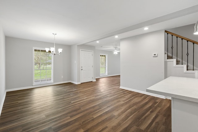 interior space featuring ceiling fan with notable chandelier, dark wood-type flooring, and a healthy amount of sunlight