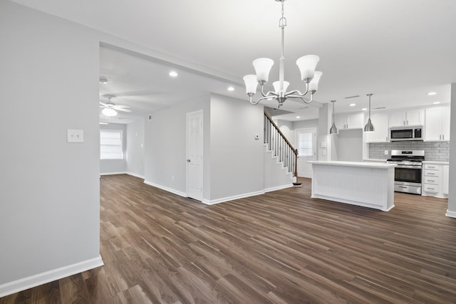 kitchen with appliances with stainless steel finishes, decorative light fixtures, white cabinets, a center island, and dark wood-type flooring