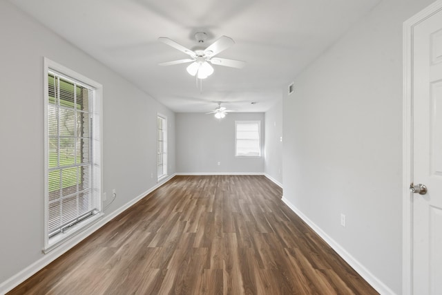 empty room with dark wood-type flooring, ceiling fan, and a healthy amount of sunlight