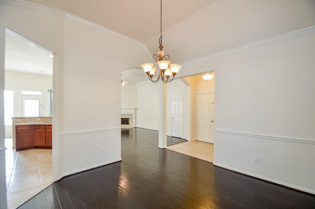 unfurnished dining area with ceiling fan with notable chandelier, lofted ceiling, light hardwood / wood-style flooring, and ornamental molding