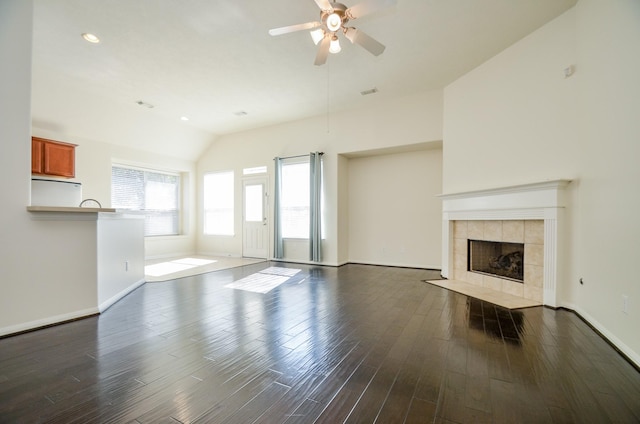 unfurnished living room with ceiling fan, vaulted ceiling, a fireplace, and dark hardwood / wood-style flooring