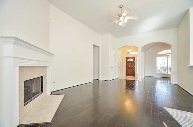 unfurnished living room featuring ceiling fan, a tiled fireplace, and hardwood / wood-style flooring