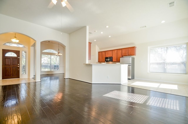 unfurnished living room with lofted ceiling, dark hardwood / wood-style floors, and ceiling fan with notable chandelier