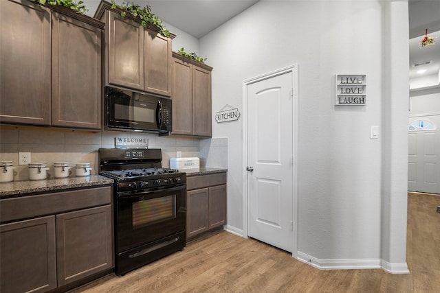 kitchen with black appliances, light wood-type flooring, backsplash, dark stone counters, and dark brown cabinetry