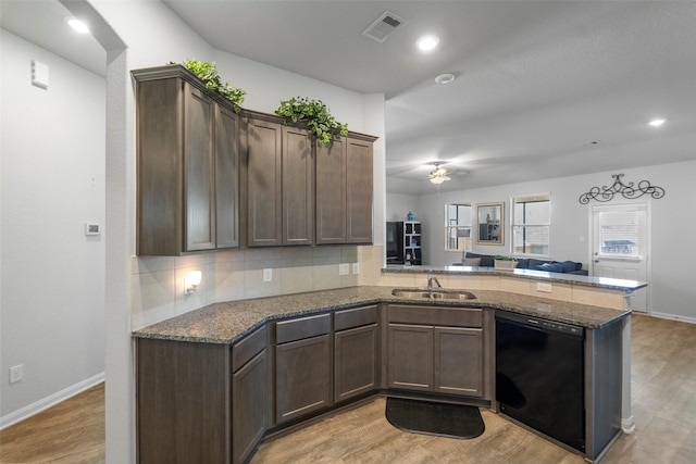 kitchen with kitchen peninsula, light hardwood / wood-style flooring, tasteful backsplash, black dishwasher, and sink