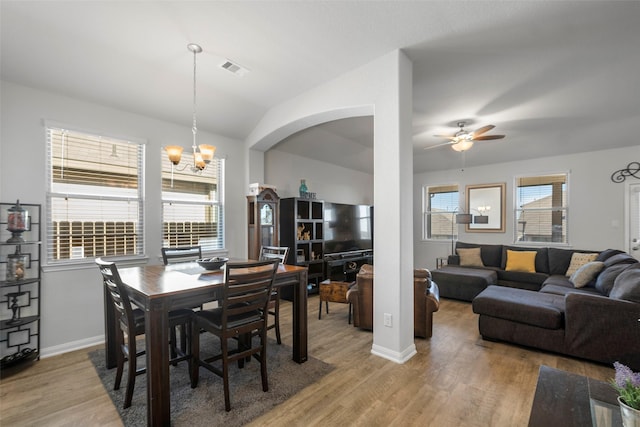 dining space with ceiling fan with notable chandelier and wood-type flooring