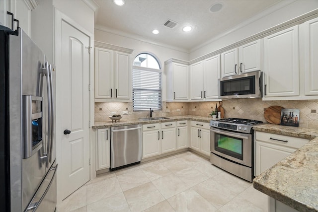 kitchen with stainless steel appliances, white cabinetry, sink, and backsplash