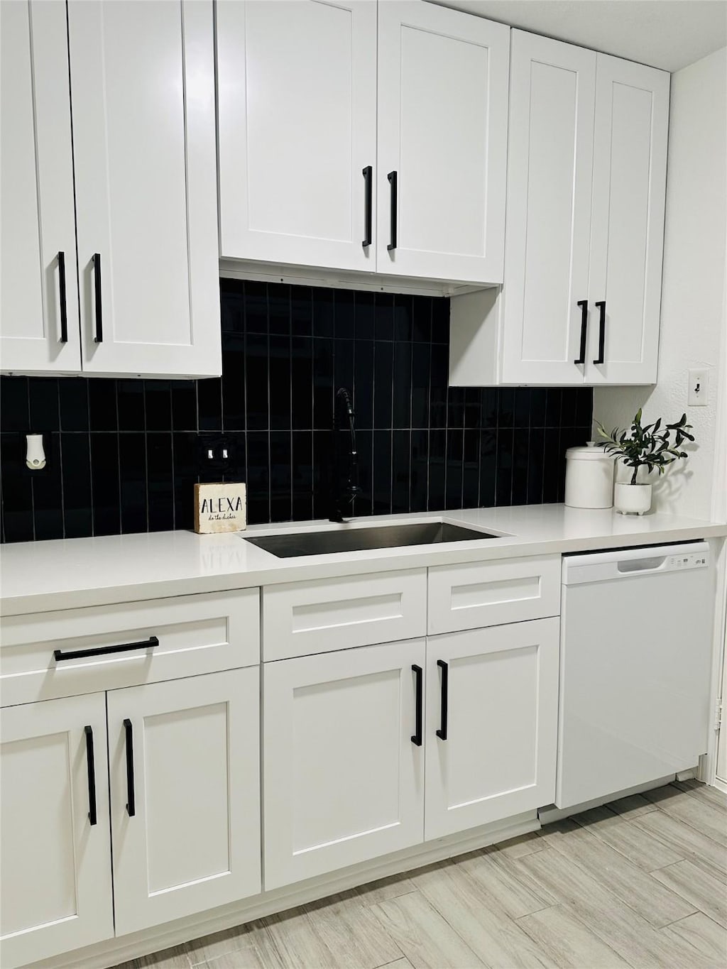 kitchen featuring white cabinets, dishwasher, tasteful backsplash, and sink