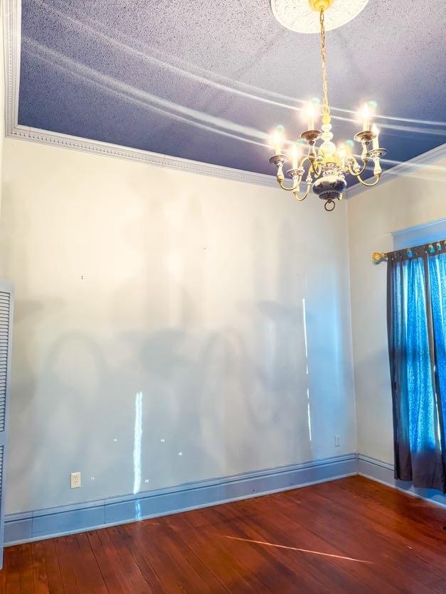 unfurnished room featuring hardwood / wood-style floors and a notable chandelier