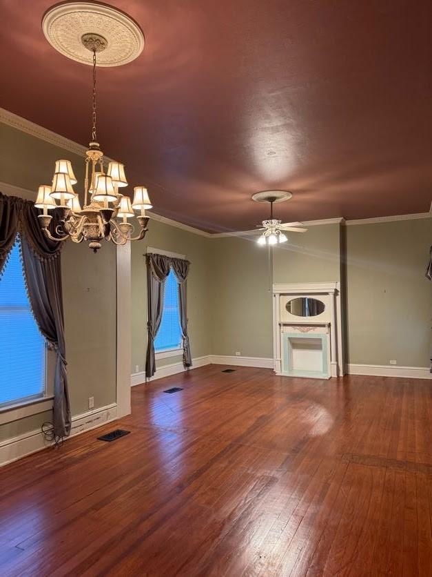 unfurnished living room with crown molding, ceiling fan with notable chandelier, and hardwood / wood-style flooring