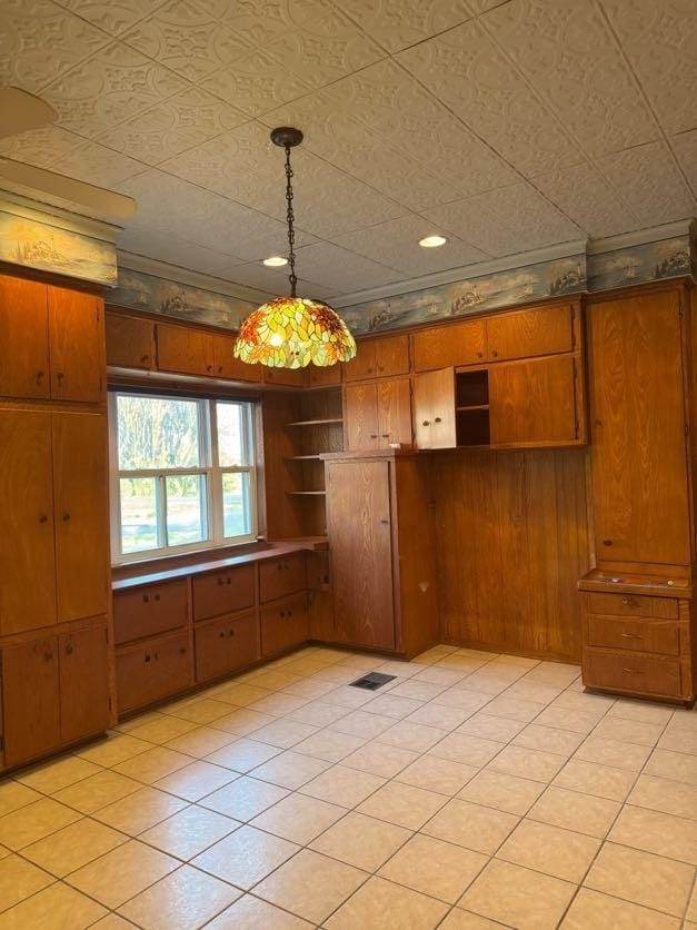 kitchen with wood walls, light tile patterned flooring, and pendant lighting