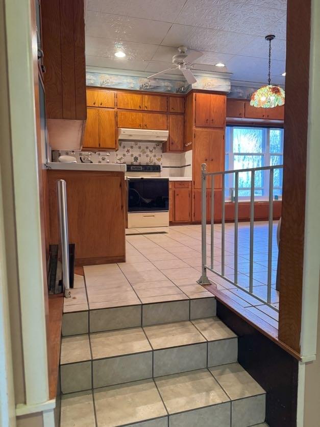 kitchen featuring pendant lighting, light tile patterned floors, tasteful backsplash, white electric stove, and ceiling fan