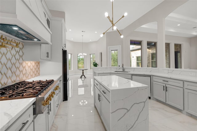 kitchen with a kitchen island, decorative light fixtures, dishwashing machine, custom range hood, and an inviting chandelier