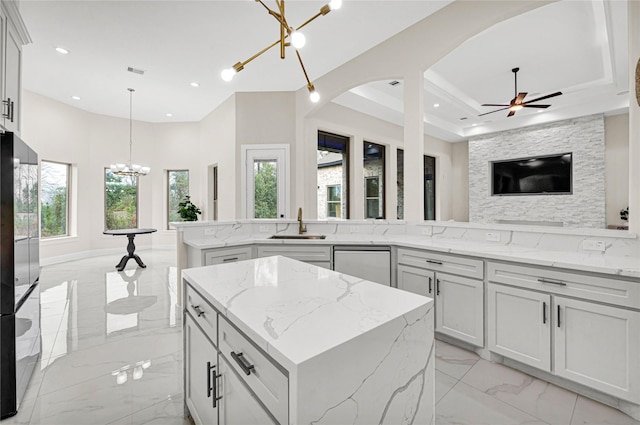 kitchen featuring pendant lighting, a center island, stainless steel dishwasher, and light stone counters